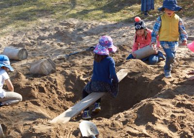 preschool children digging a huge pit and making a balance beam